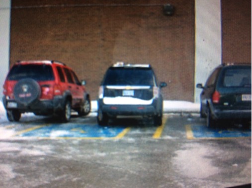 Car double parked between two designated wheelchair accessible spots.
